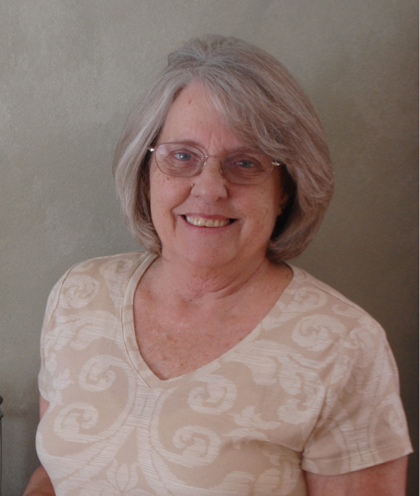 Portrait of a woman in glasses smiling, and wearing a tan top